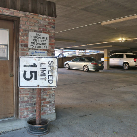 a parking garage with a sign and cars in the background