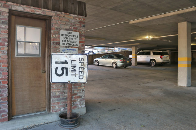 a parking garage with a sign and cars in the background