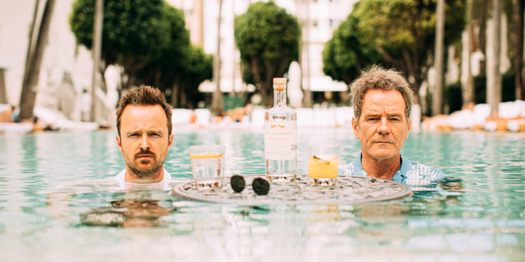 two men in a pool with drinks and a table