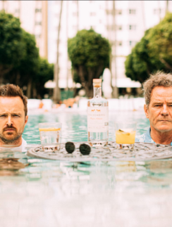 two men in a pool with drinks and a table