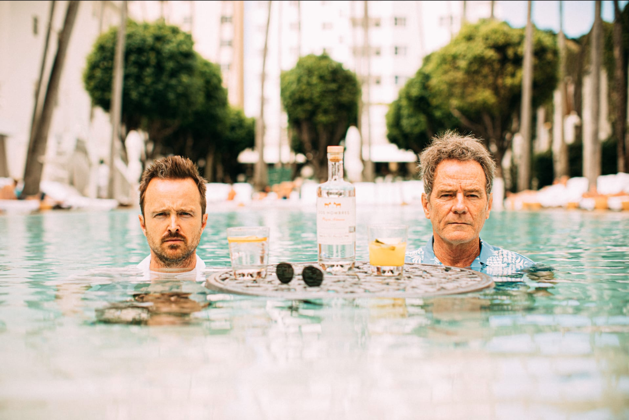two men in a pool with drinks and a table