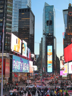 a large crowd of people in a busy city street with Times Square in the background
