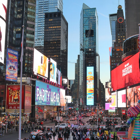 a large crowd of people in a busy city street with Times Square in the background