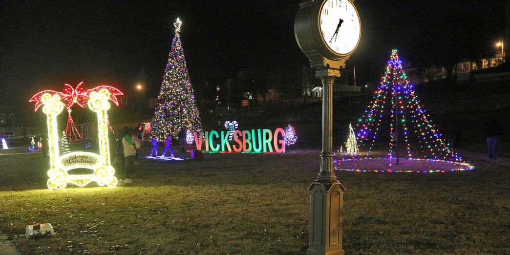 a clock in a park with christmas lights