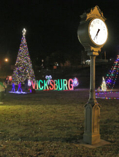 a clock in a park with christmas lights