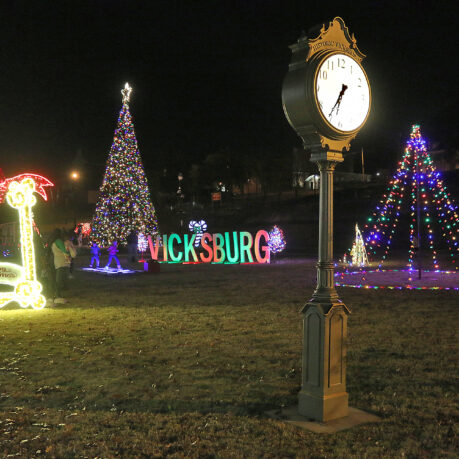 a clock in a park with christmas lights