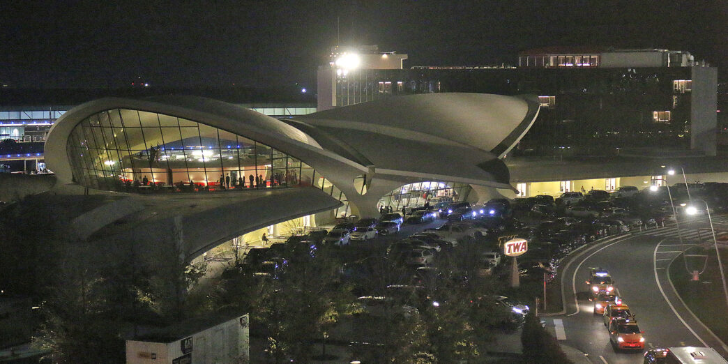 a building with a curved roof and a parking lot with cars parked in front