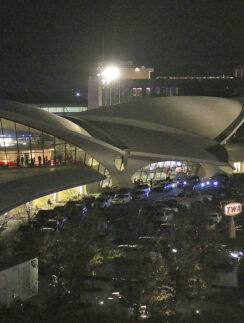 a building with a curved roof and a parking lot with cars parked in front