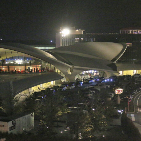 a building with a curved roof and a parking lot with cars parked in front