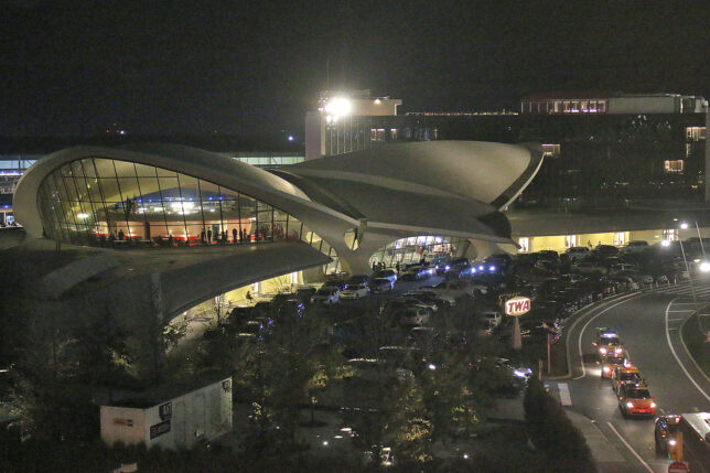 a building with a curved roof and a parking lot with cars parked in front