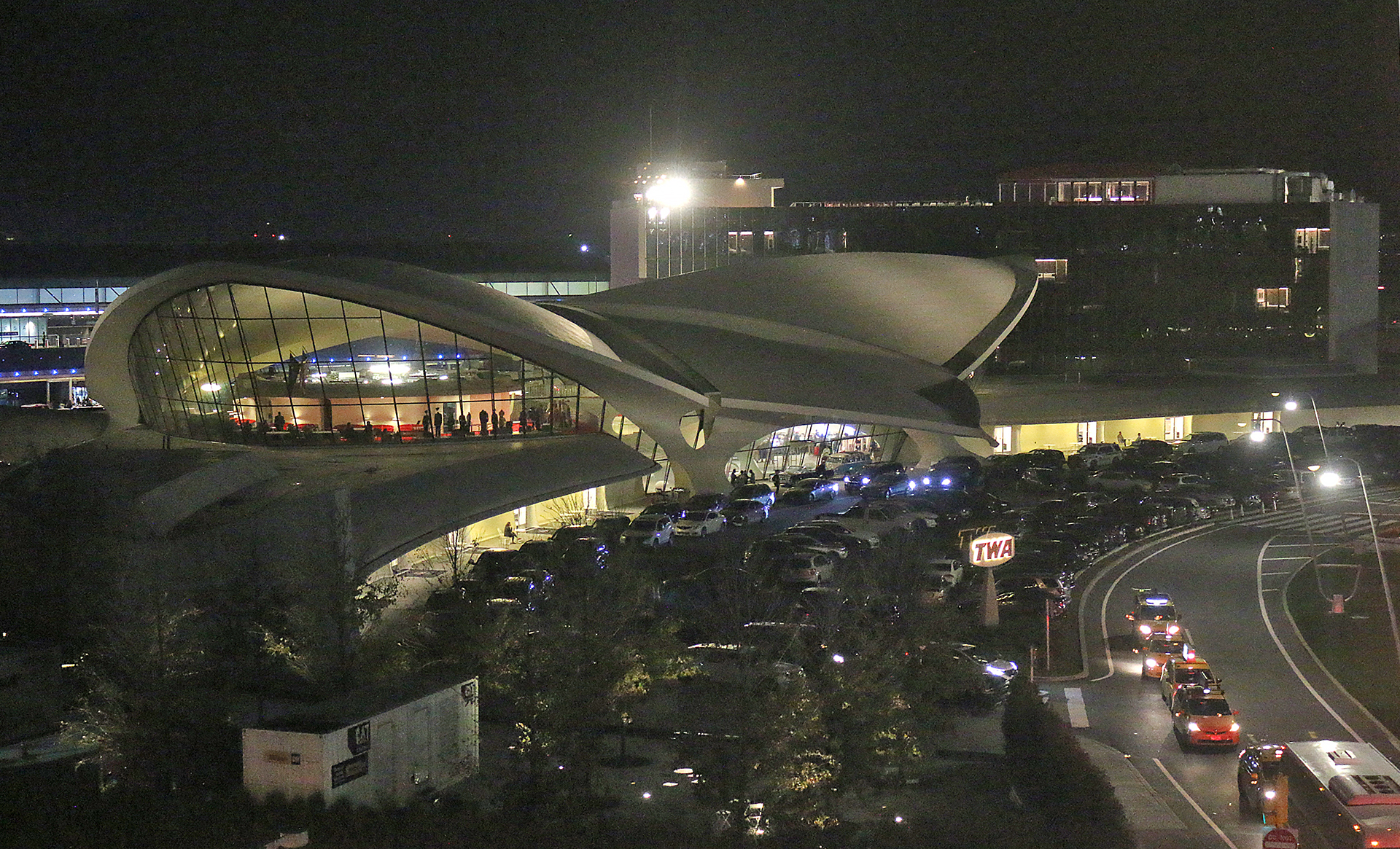 a building with a curved roof and a parking lot with cars parked in front