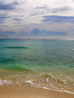 a beach with blue water and clouds