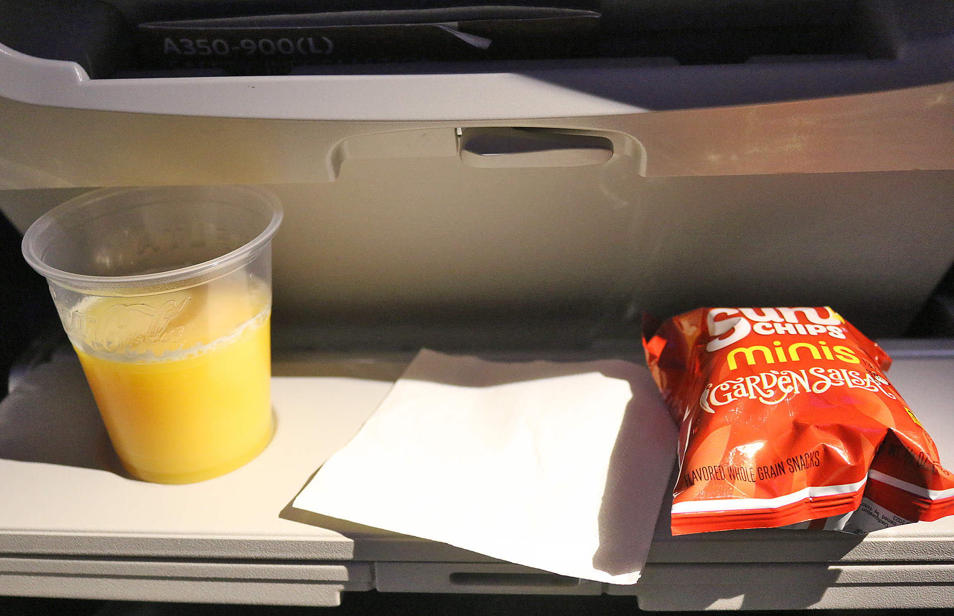 a plastic cup and a packet of chips on a tray