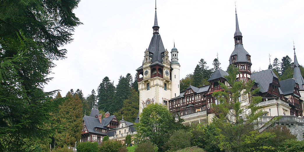 a castle with trees around it with Peleș Castle in the background