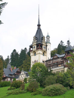a castle with trees around it with PeleÈ™ Castle in the background