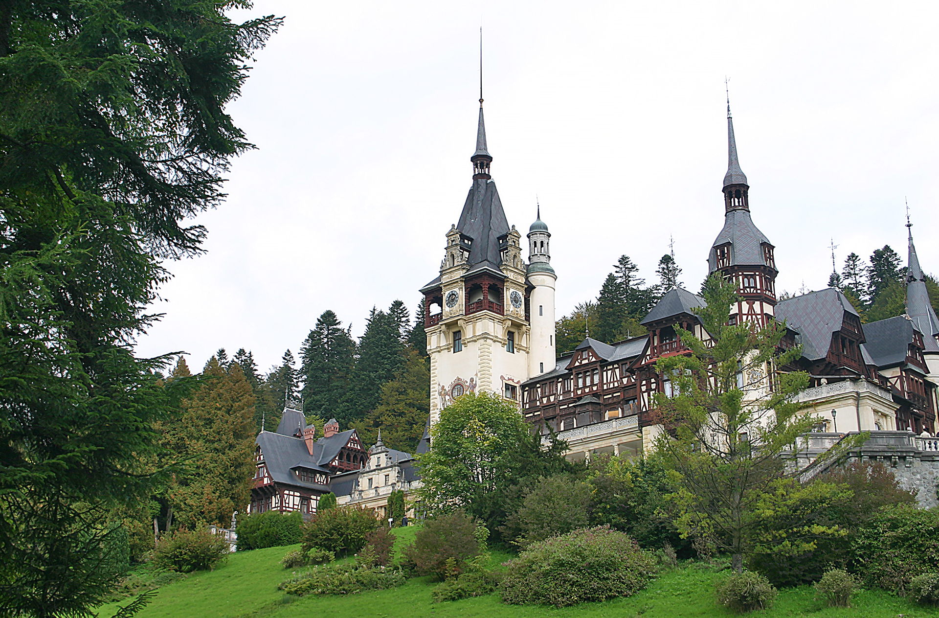 a castle with trees around it with Peleș Castle in the background