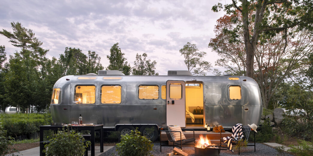 a camper trailer with a fire pit and trees