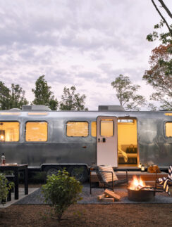 a camper trailer with a fire pit and trees
