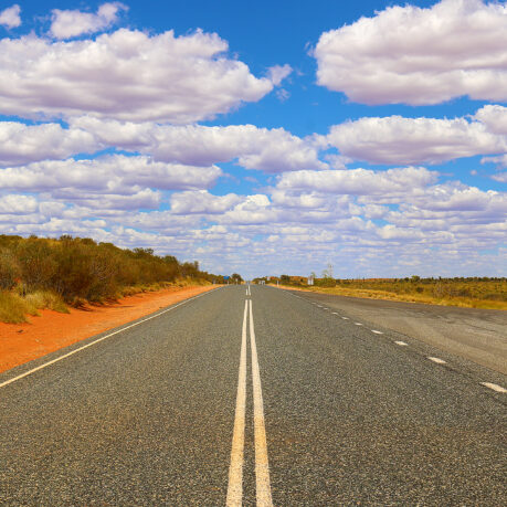 a road with a white line on the side with Nullarbor Plain in the background