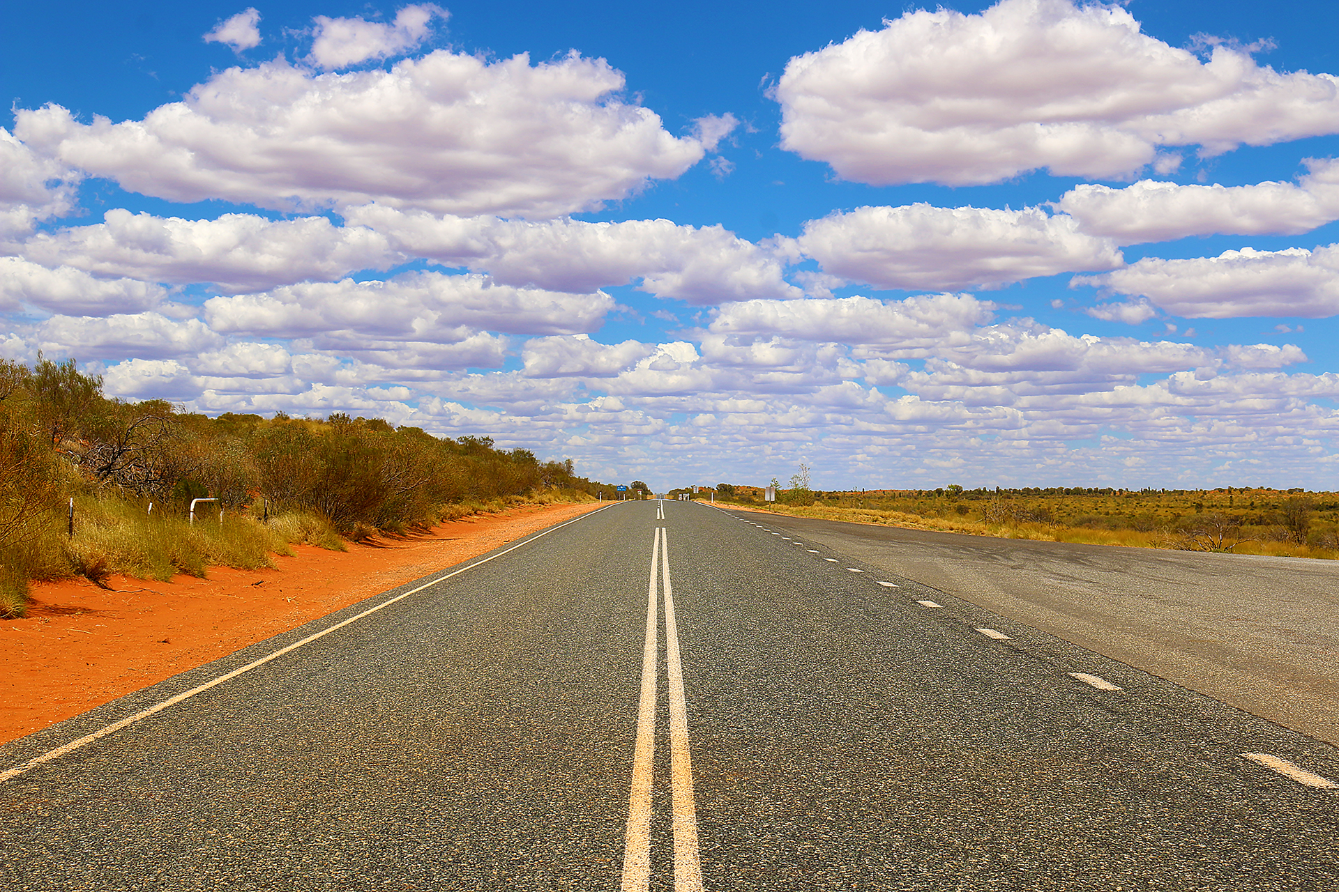 a road with a white line on the side with Nullarbor Plain in the background