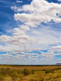 a landscape with a large field and blue sky with clouds