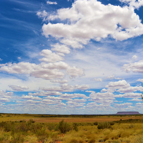 a landscape with a large field and blue sky with clouds