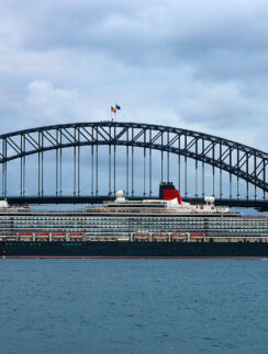 a large ship in the water with Sydney Harbour Bridge in the background