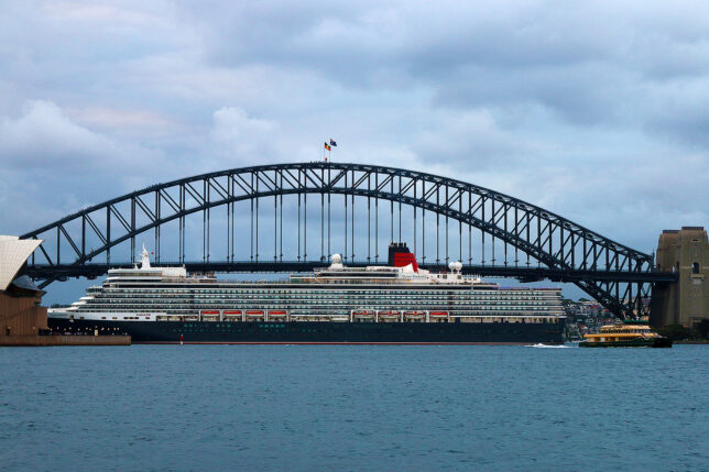 a large ship in the water with Sydney Harbour Bridge in the background