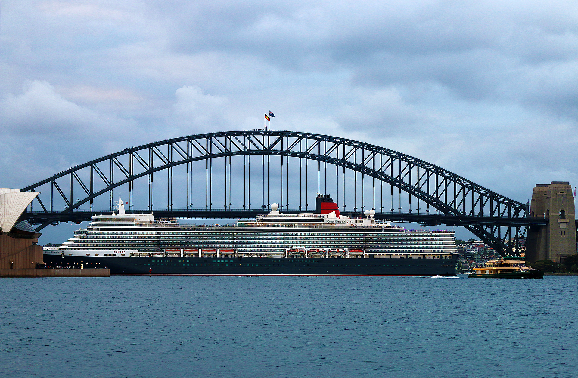 a large ship in the water with Sydney Harbour Bridge in the background