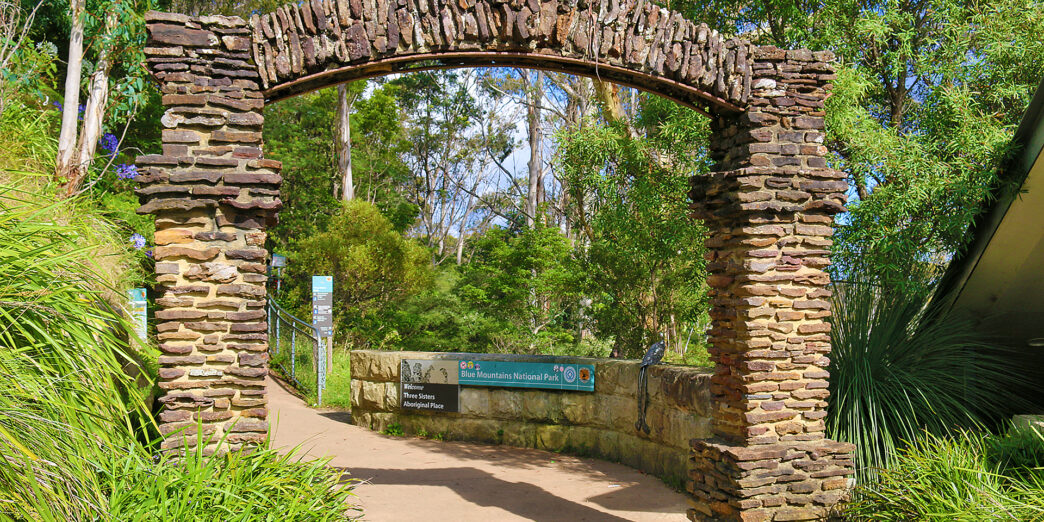 a stone archway with a sign in the middle of a path