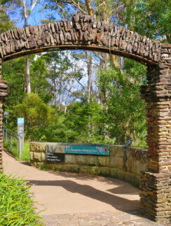a stone archway with a sign in the middle of a path