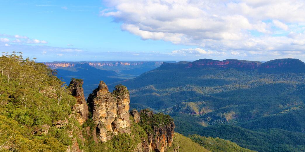 a rocky cliff with trees and mountains in the background