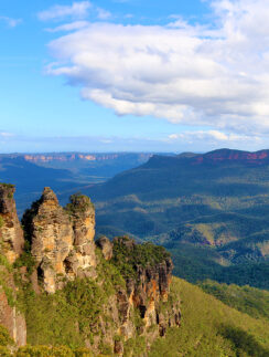 a rocky cliff with trees and mountains in the background