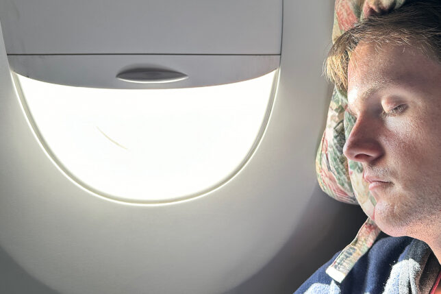 a person sitting in an airplane with a light in the window