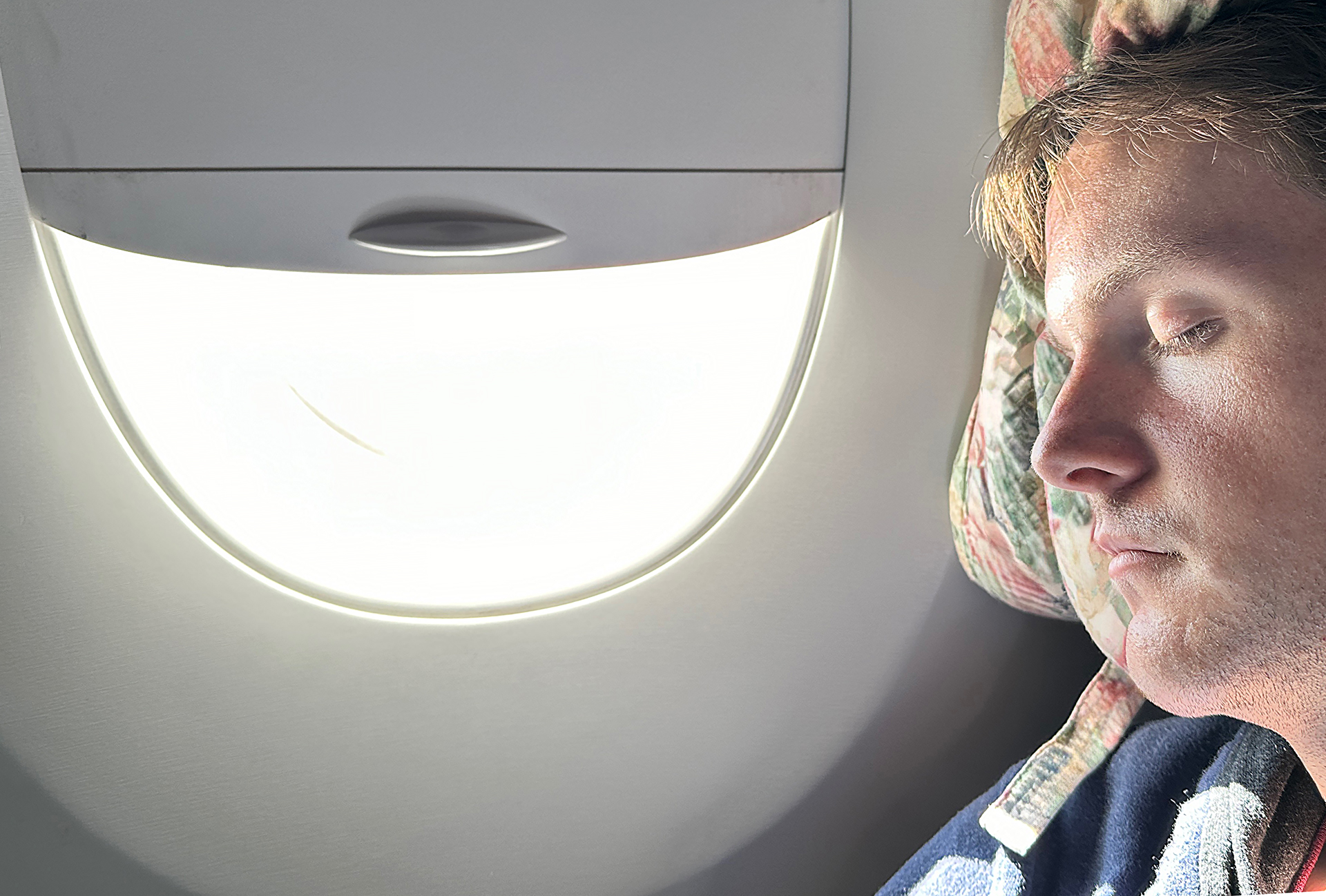 a person sitting in an airplane with a light in the window