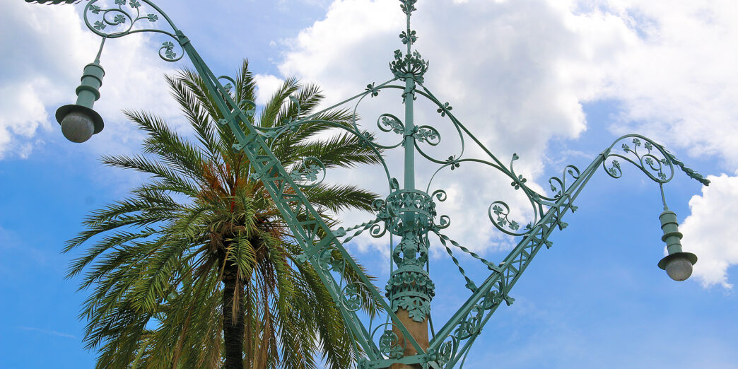 a metal pole with a palm tree in the background