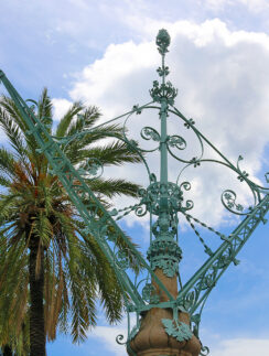 a metal pole with a palm tree in the background
