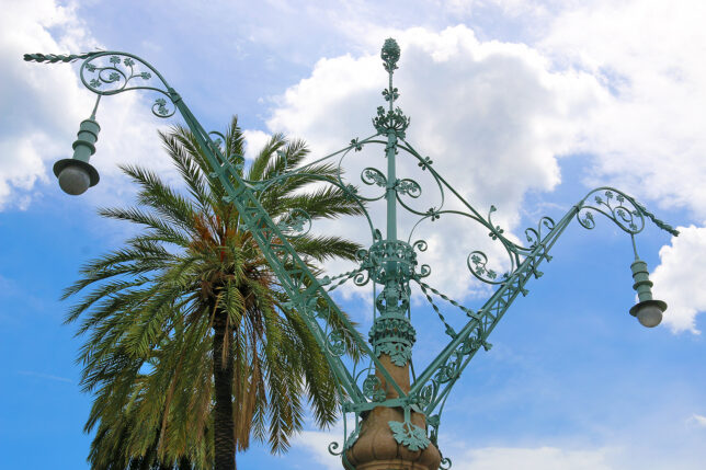 a metal pole with a palm tree in the background