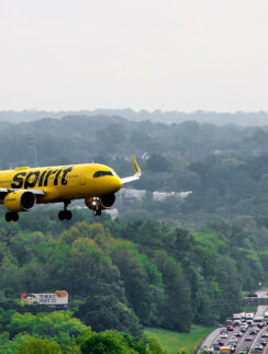 a yellow airplane flying over a highway
