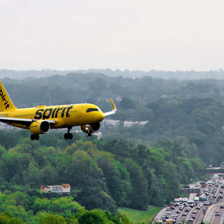 a yellow airplane flying over a highway