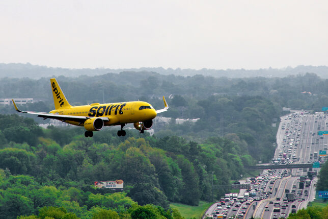a yellow airplane flying over a highway
