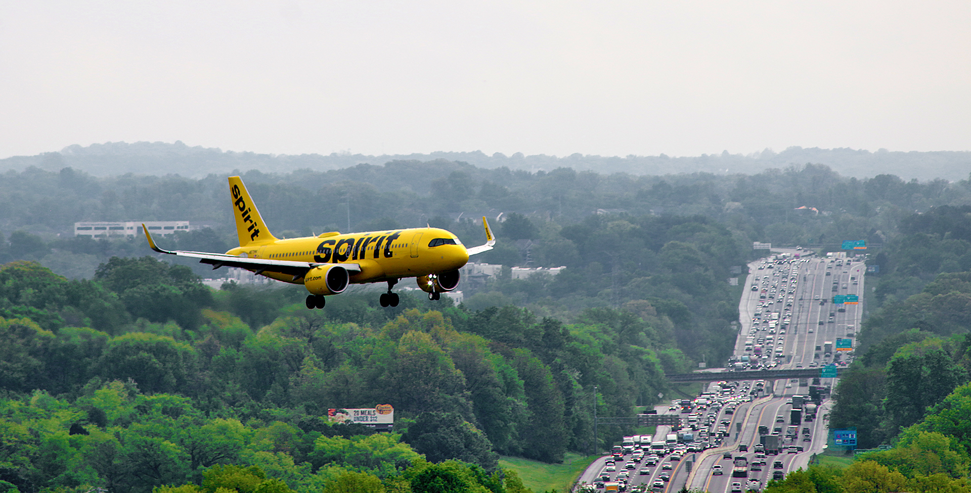 a yellow airplane flying over a highway