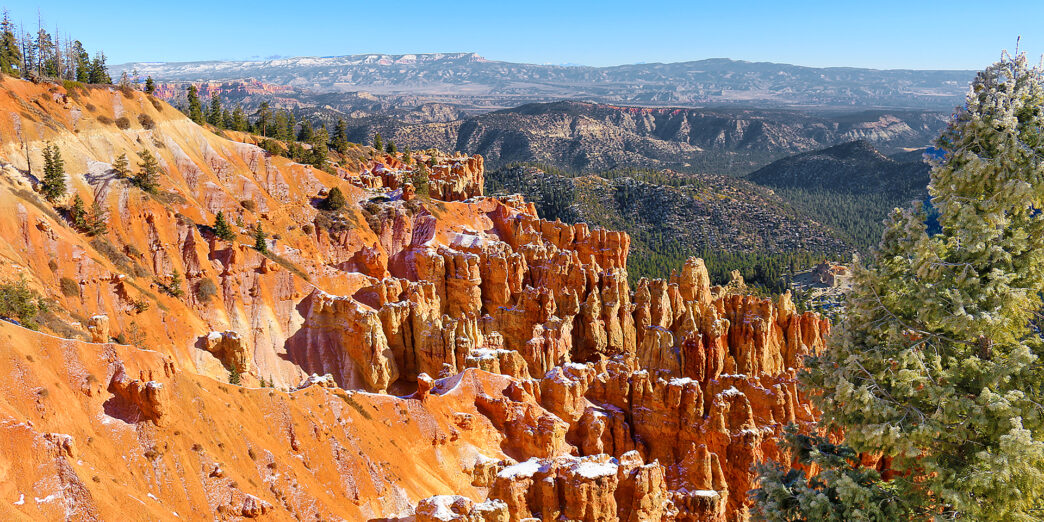 a rocky mountains with trees and snow with Bryce Canyon National Park in the background