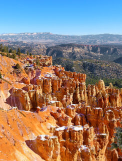 a rocky mountains with trees and snow with Bryce Canyon National Park in the background