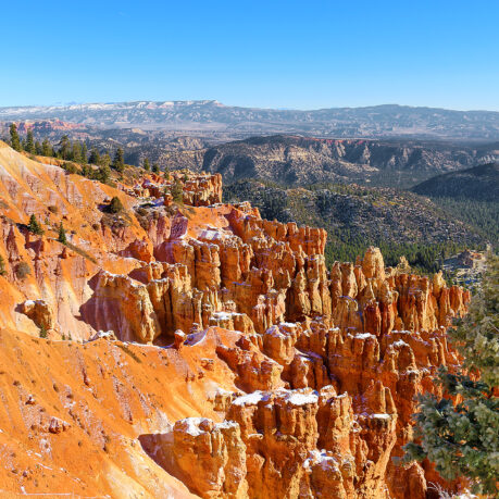a rocky mountains with trees and snow with Bryce Canyon National Park in the background