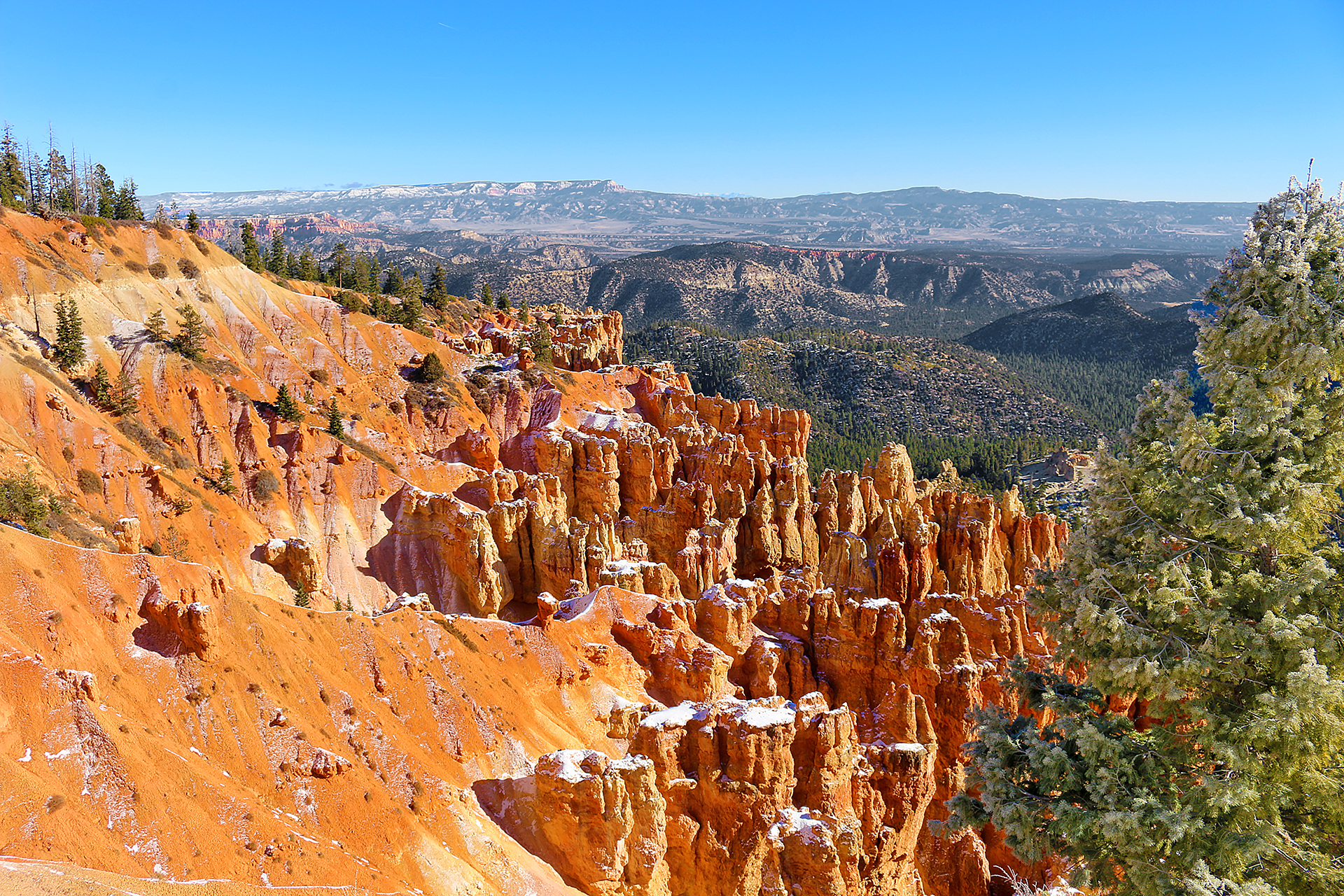 a rocky mountains with trees and snow with Bryce Canyon National Park in the background