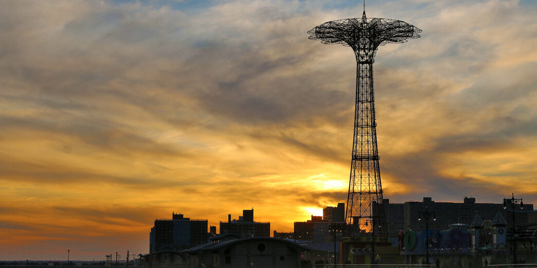 a tall metal tower with a city in the background