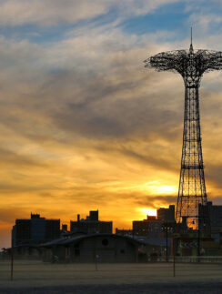 a tall metal tower with a city in the background