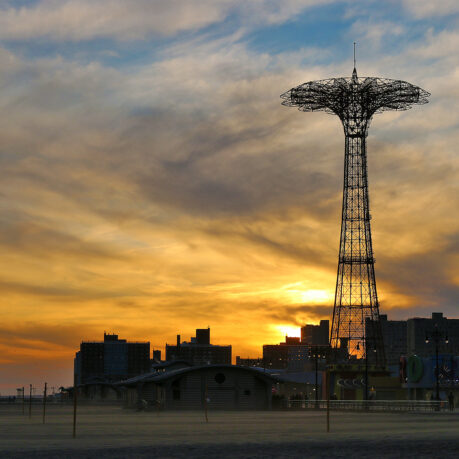 a tall metal tower with a city in the background