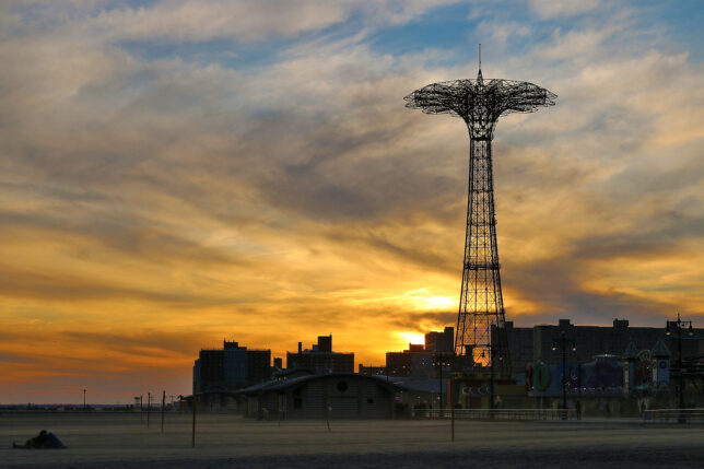 a tall metal tower with a city in the background